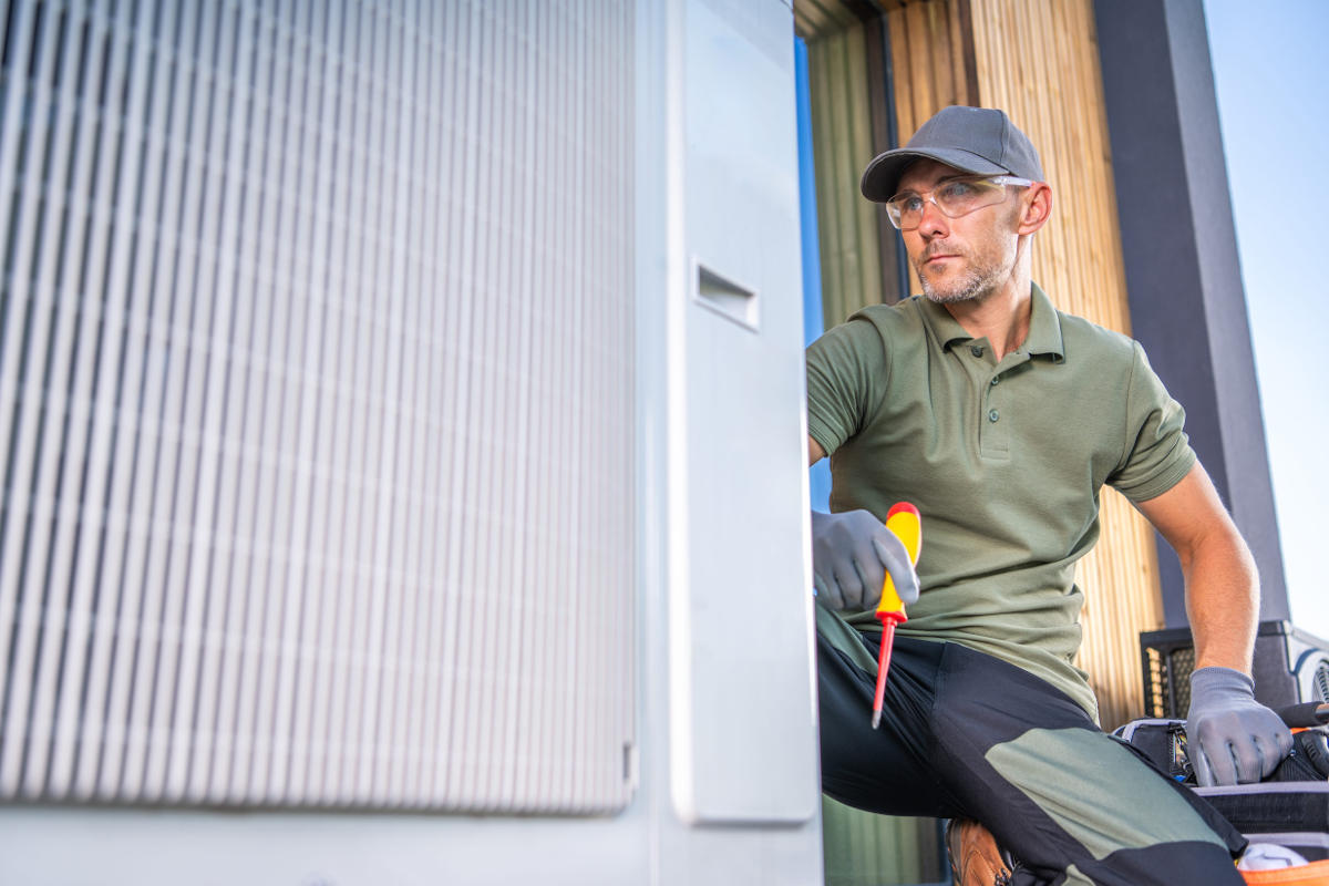 Technician in green polo shirt performing maintenance on air conditioning unit