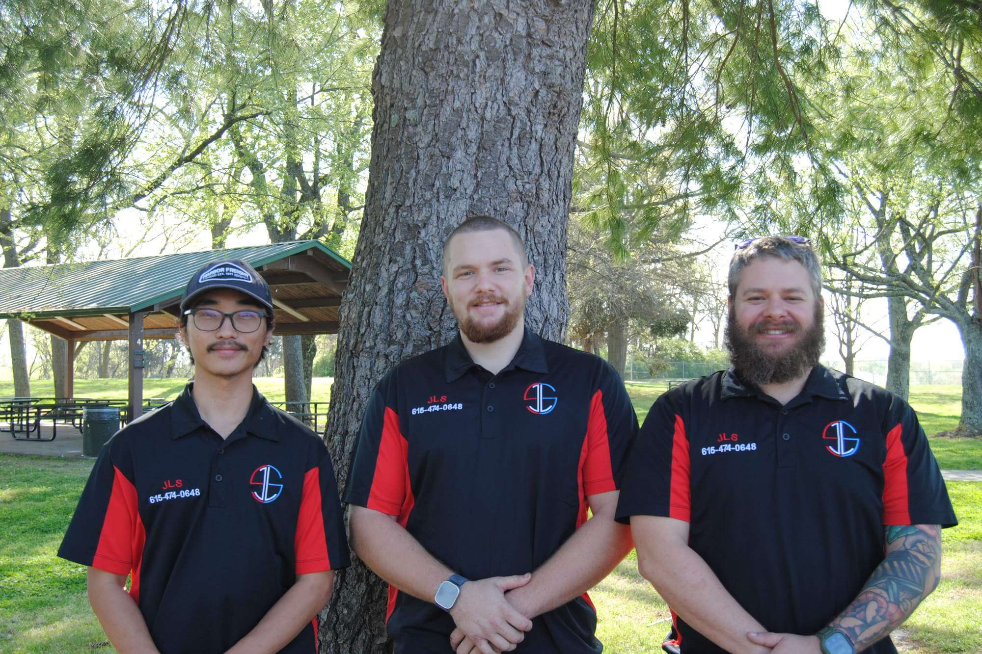 Three JLS service technicians standing in front of a tree and smiling